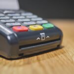Commerciante che utilizza un POS per un pagamento, con focus sulle nuove regole introdotte.