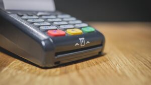 Commerciante che utilizza un POS per un pagamento, con focus sulle nuove regole introdotte.