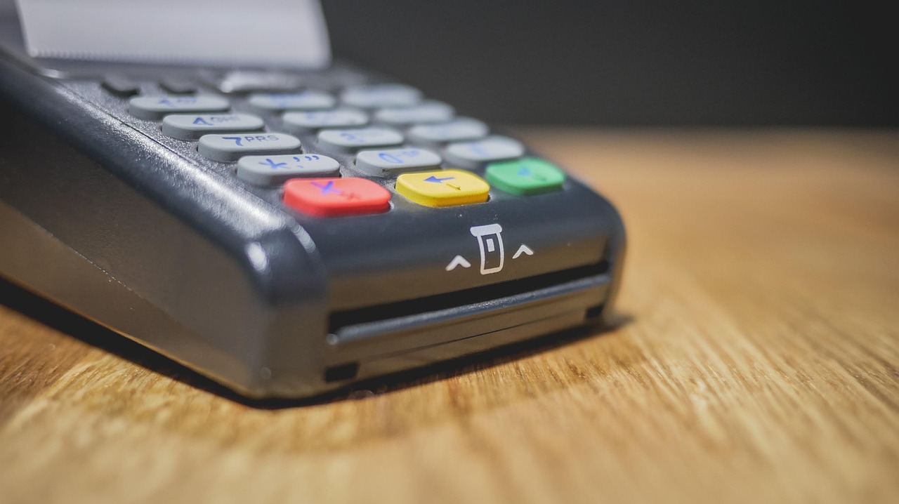 Commerciante che utilizza un POS per un pagamento, con focus sulle nuove regole introdotte.