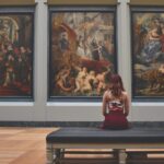 Investitore osserva opere d'arte in galleria, esplorando strategie per diversificare il portafoglio nel 2026.
